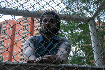 Young tattooed man standing next to a soccer goal in a park surrounded by nature