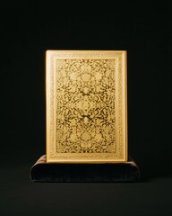 Intricate Golden Book with Ornate Cover on Velvet Pedestal Against Black Background