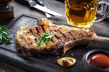 Pork chop and beer on cutting board with rosemary garnish