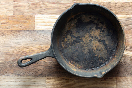 Old rusty cast iron frying pan background. On a wooden chopping cutting board. - Powered by Adobe