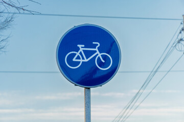 A blue bicycle lane sign stands prominently against a clear sky, signaling the presence of a...