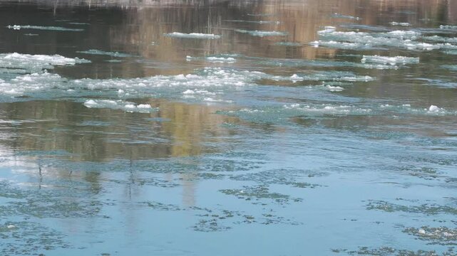 Drifting ice on broad river. Melting blocks quickly float on the water on sunny day