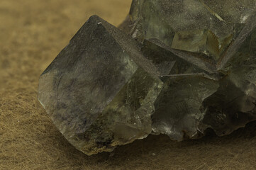 An impressive cluster of fluorite crystals exhibiting a translucent green hue and distinct cubic formations, set against a tan background
