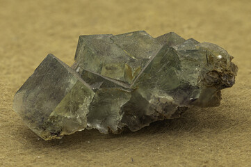 cluster of green fluorite crystals with sharp cubic structures and translucent textures, beautifully contrasted against a simple tan background, emphasizing its natural form