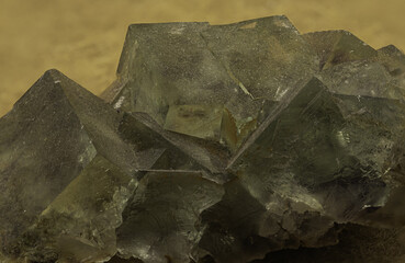 An impressive cluster of fluorite crystals exhibiting a translucent green hue and distinct cubic formations, set against a tan background