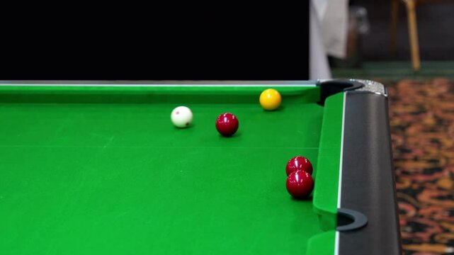 pocket a yellow ball in blackball Pool game on a green cloth pool table, hit by the cue pocketing a yellow ball