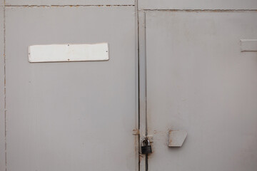 Large grey metal doors with a padlock, showing the industrial texture