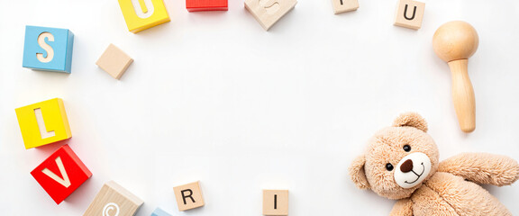 Obraz premium Playful wooden toy blocks and teddy bear on white background, childhood joy