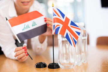 Little flag of Great Britain on table with bottles of water and flag of Iraq put next to it by...