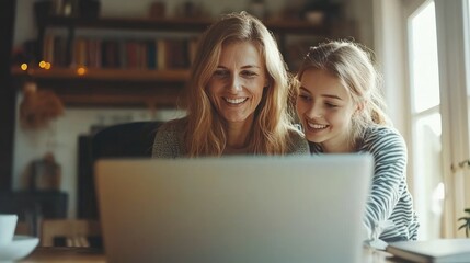 Smiling mother and daughter enjoying time together while using a laptop at home