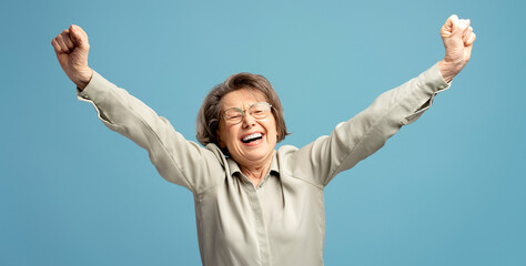 Happy senior woman celebrating with arms raised and fists clenched