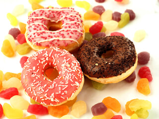 Pink and chocolate donuts on colorful sweet candy jelly. High level of sugar products. Popular international sweets.