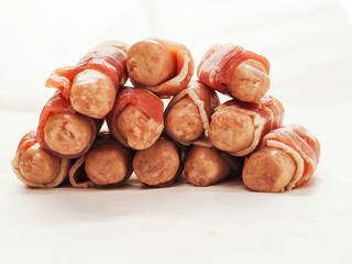 Stack of pigs in blanket on white background. Simple pork meat party food or starter.