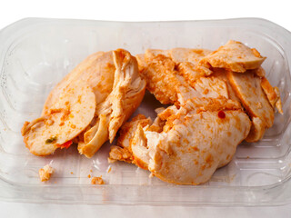 A tray of Cajun style chicken is on a white background. The chicken is cut into pieces. Small portion of poultry meat, ready to be eat or used for a sandwich.