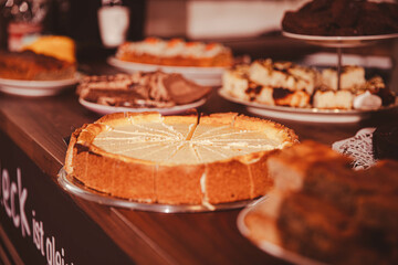 Assorted cheesecakes and pastries on wooden table in warm lighting