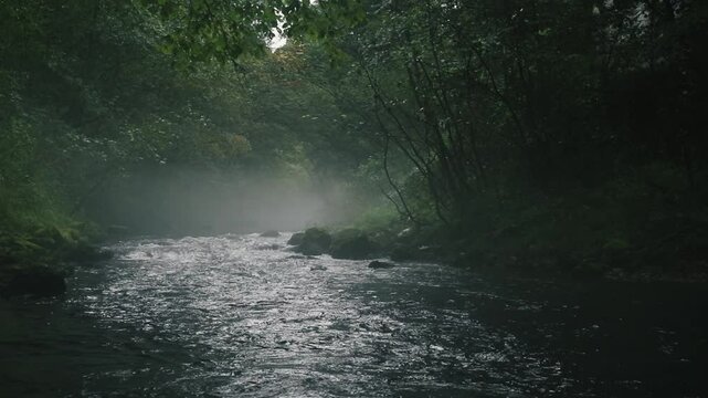 Misty river flowing through rapids. Movie like slow motion of free water rushing down the stream, wet, haze, mist. Spooky river