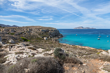 Cala Rossa Bay on Favignana Island, Sicily, with turquoise waters, sandy beach, rocky coastline, anchored boats, and a scenic Mediterranean backdrop under a clear sky