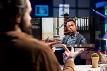 IT admin working from home in videocall with african american coworker, testing programs and systems. Programmer checking code with colleague in online teleconference, sitting at desk in apartment