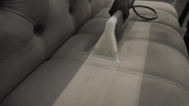 Cleaner is dry-cleaning sofa using extractor machine with detergent 4k video. Using extractor to refresh and clean from dust and stains upholstered furniture.