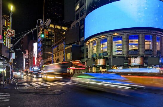 Busy intersection with cars, buses and taxis driving down 42nd Street through Times Square in New York City at night