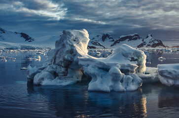 Antarctic Peninsula: Snowy peaks, icebergs, cloudy sky. Lemaire Channel