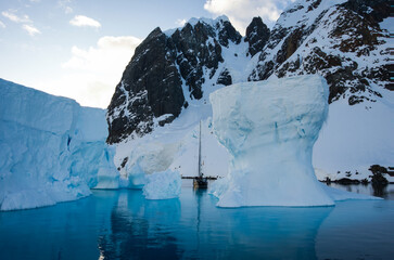Antarctic Peninsula: Snowy peaks, icebergs, cloudy sky. Lemaire Channel