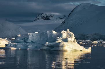 Antarctic Peninsula: Snowy peaks, icebergs, cloudy sky. Lemaire Channel