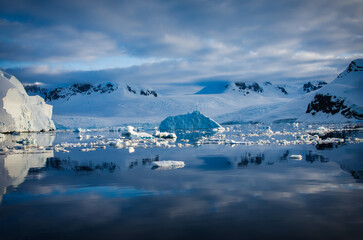 Antarctic Peninsula: Snowy peaks, icebergs, cloudy sky. Lemaire Channel