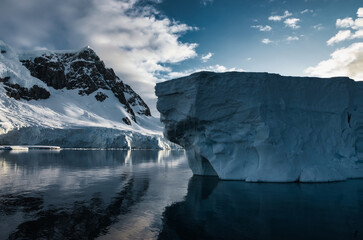 Antarctic Peninsula: Snowy peaks, icebergs, cloudy sky. Lemaire Channel