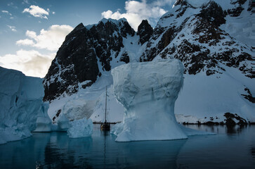 Antarctic Peninsula: Snowy peaks, icebergs, cloudy sky. Lemaire Channel
