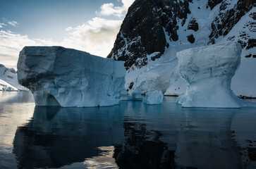 Antarctic Peninsula: Snowy peaks, icebergs, cloudy sky. Lemaire Channel