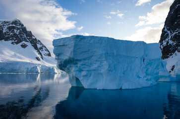 Antarctic Peninsula: Snowy peaks, icebergs, cloudy sky. Lemaire Channel