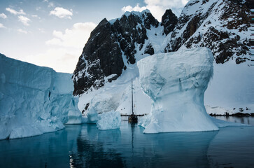 Antarctic Peninsula: Snowy peaks, icebergs, cloudy sky. Lemaire Channel