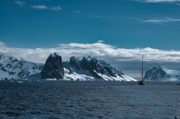 Antarctic Peninsula: Snowy peaks, icebergs, cloudy sky. Lemaire Channel