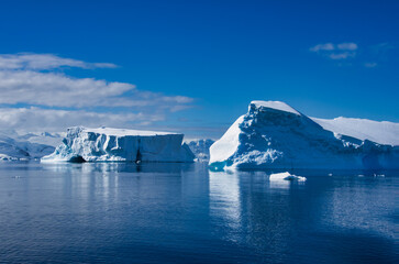 Antarctic Peninsula: Snowy peaks, icebergs, cloudy sky. Lemaire Channel