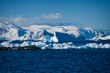 Antarctic Peninsula: Snowy peaks, icebergs, cloudy sky. Lemaire Channel