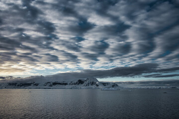 Antarctic Peninsula: Snowy peaks, icebergs, cloudy sky. Lemaire Channel