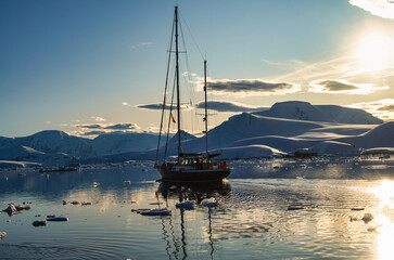 Antarctic Peninsula, A sailboat navigates choppy waters near snowy Antarctic mountains.