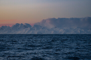 Antarctic Peninsula, Drake Passage:  Snowy mountains, calm sea.