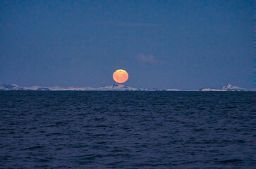 Antarctic Peninsula, Drake Passage:  Sunrise/sunset, orange moon.