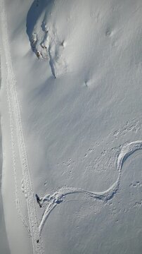 Vertical Drone Shot of a Woman Playing in the Snow, Revealing a Stunning Mountain Landscape and an Abandoned Base &ndash; 9:16 4K