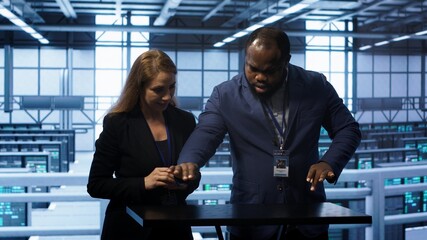 System administrators looking at holograms in data center, doing swiping motions hand gestures. Server farm workplace employees interacting with augmented reality tech, camera A