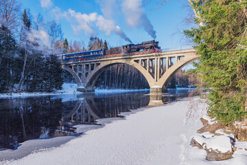 Retro steam train moves above the river.