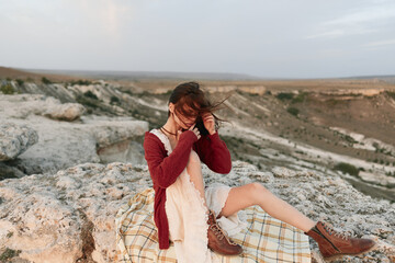Woman enjoying serenity and beauty of nature in red dress and boots on mountain top with blanket