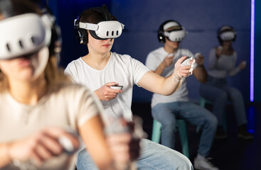 In dark hall of entertainment center, young guys and girls talking about spending time in virtual...