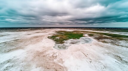 Aerial view of an icy pond in winter under a cloudy sky, in a vast and deserted, snow-covered landscape