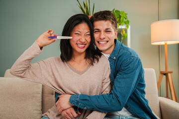 Joyful couple celebrating the exciting news of a positive pregnancy test with bright smiles and laughter, embodying happiness and love as they embrace their journey into parenthood together