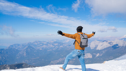 Freedom and Adventure: man Hiker with Arms Spread on Snowy Mountain Peak