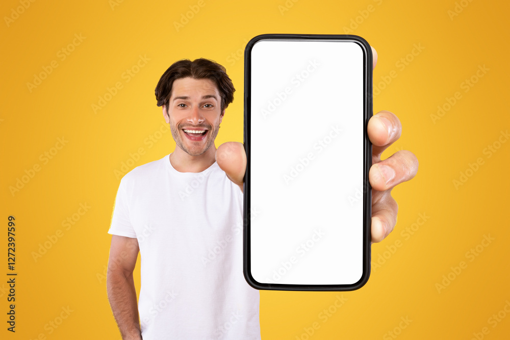 Poster Mobile App Advertisement. Handsome Excited Man Showing White Empty Smartphone Screen Recommending App Posing Over Orange Studio Background, Smiling To Camera. Check This Out, Cellphone Display Mock Up