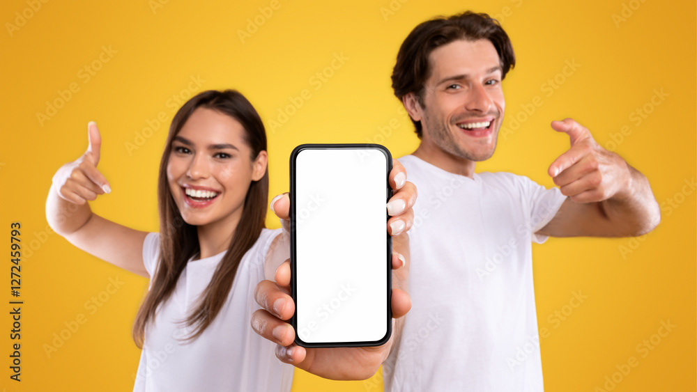 Poster use this new application. portrait of cheerful millennial couple pointing at smartphone with white s